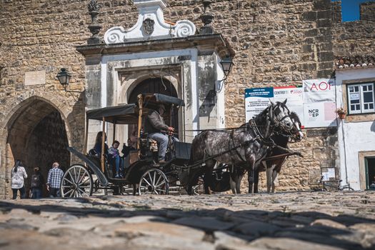 Obidos, Portugal - April 12, 2019: Horse-drawn carriage carrying tourists at the entrance to the medieval side on a spring day