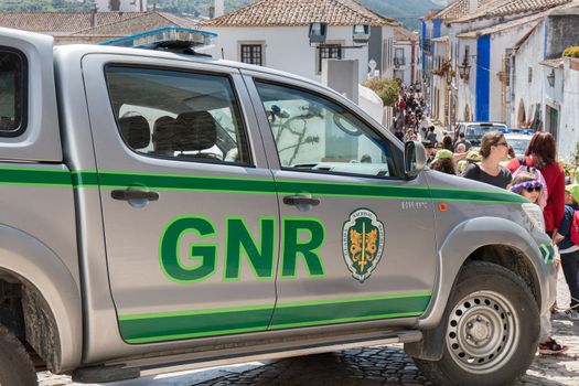 Obidos, Portugal - April 12, 2019: car of the Republican National Guard (GNR) parked in the middle of a pedestrian street where tourists pass on a spring day