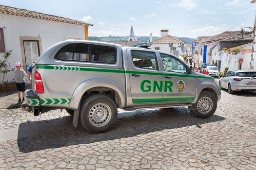 Obidos, Portugal - April 12, 2019: car of the Republican National Guard (GNR) parked in the middle of a pedestrian street where tourists pass on a spring day