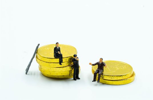 miniature figure a group of business men sitting on top of pile stack of golden coins. business success concept