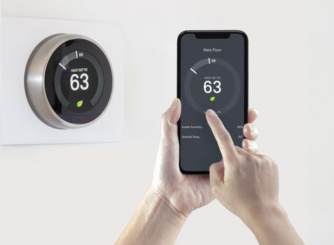 A person using a smart phone application saving energy with a wireless smart thermostat on a white background.