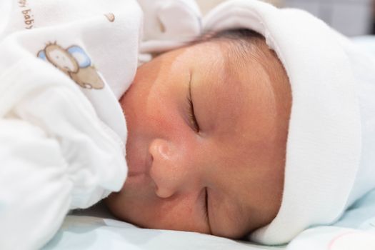 Sleeping cute New Born Baby infant with white baby cloth on the bed