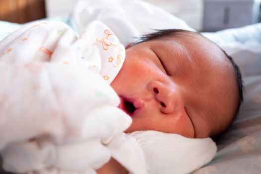 Sleeping cute New Born Baby infant with white baby cloth on the bed