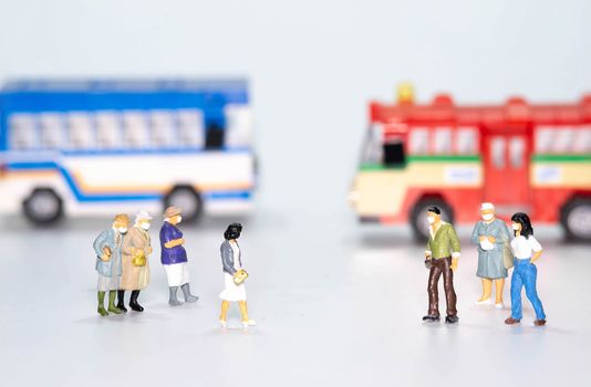 the miniature figure doll people wearing face mask  to protect Coronavirus or Covid-19 with bus in back isolate on white background