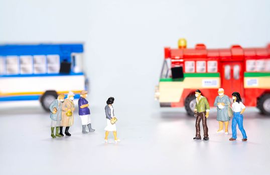 the miniature figure doll people wearing face mask  to protect Coronavirus or Covid-19 with bus in back isolate on white background