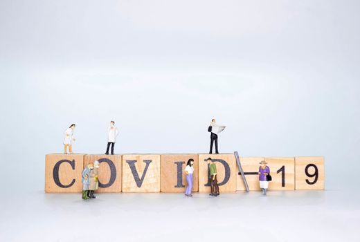 Wooden Alphabet word COVID-19 with miniature figure doll of people and doctoe nurse wearing face mask  isolate on White background