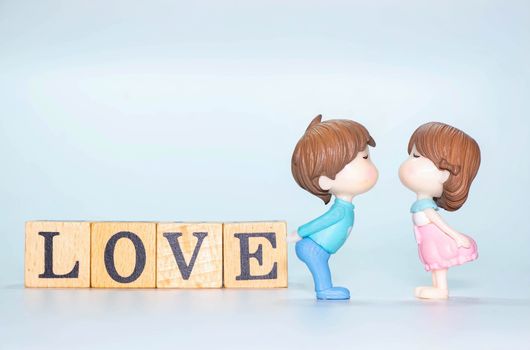 Miniature doll of couple boy and girl kiss and have Wooden alphabet word LOVE isolate on White background