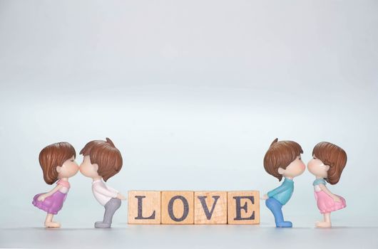 Miniature doll of couple boy and girl kiss and have Wooden alphabet word LOVE isolate on White background
