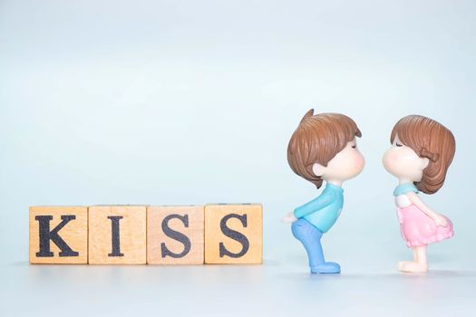 The Miniature doll of couple boy and girl kiss and have Wooden alphabet word KISS isolate on White background