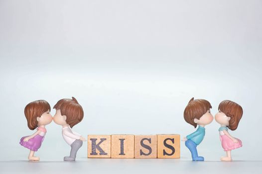 The Miniature doll of couple boy and girl kiss and have Wooden alphabet word KISS isolate on White background