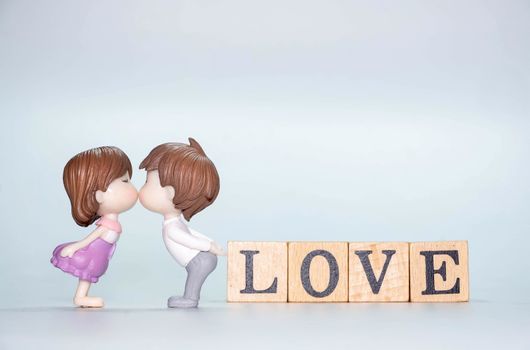 Miniature doll of couple boy and girl kiss and have Wooden alphabet word LOVE isolate on White background