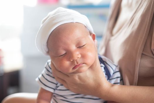 Soft focus photo of mother, mom using hand Hold baby to help a baby newborn infant belch burping after breastfeeding milk to heal gas pain or indigestion