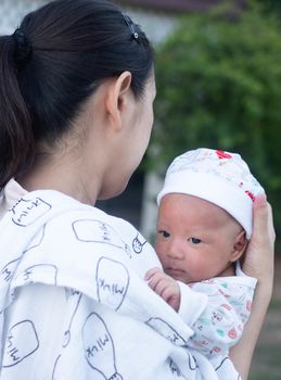 Portrait of a newborn baby infant  hold close by mother in the garden, close up. Family,