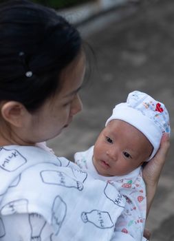 Portrait of a newborn baby infant  hold close by mother in the garden, close up. Family,