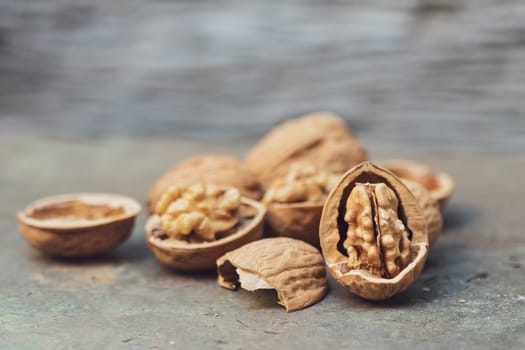 still life with Walnut kernels and whole walnuts on rustic old wooden table.