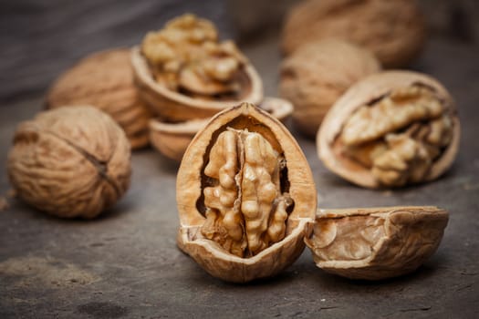 still life with Walnut kernels and whole walnuts on rustic old wooden table.