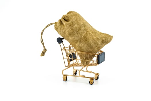 Golden shopping cart and jute bag isolated on white background