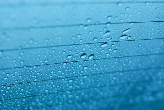 Water drops on glass window with blue background