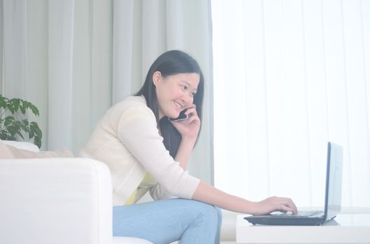 Smiling young woman freelancer working remotely from home while talking on phone.Work from home and social distance concept on virus corona pandemic.