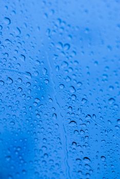 Water drops on glass window with blue background