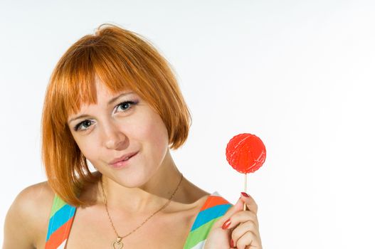 Colorful young woman with fantasy hair eating a red lollipop looking at camera. Beauty and makeup concept portrait isolated on white.