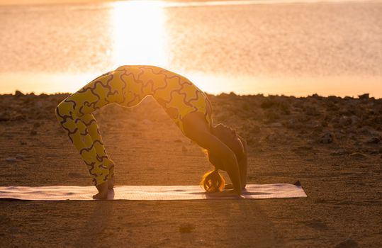 Yoga practice. Woman doing bridge pose at sunrise