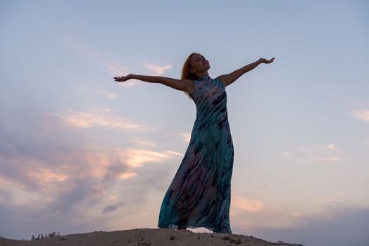 Young red woman wearing long dress on a beach