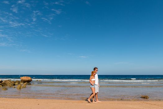 Romantic young couple walking on the beach with bare feet