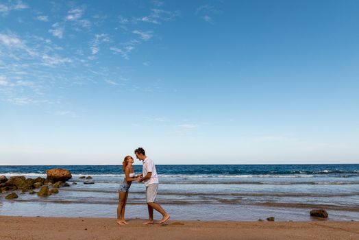 Romantic young couple walking on the beach with bare feet