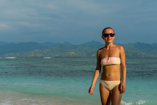 Young woman walking along tropical beach at Gili islands, Indonesia