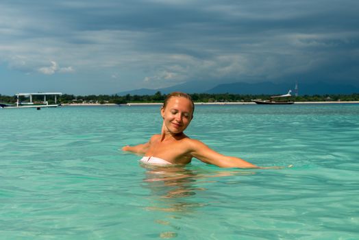 Woman at tropical island beach swimming in lush blue water