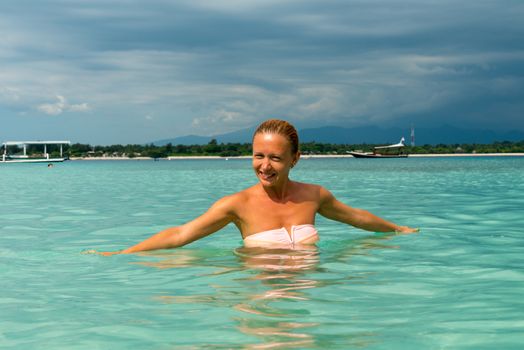 Woman at tropical island beach swimming in lush blue water