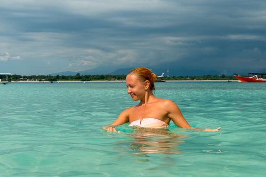 Woman at tropical island beach swimming in lush blue water