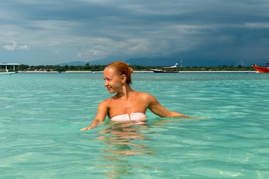 Woman at tropical island beach swimming in lush blue water