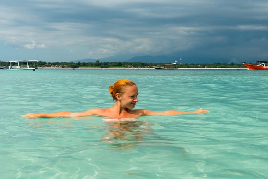 Woman at tropical island beach swimming in lush blue water