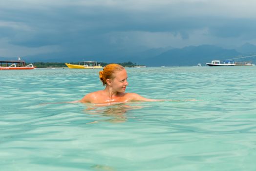 Woman at tropical island beach swimming in lush blue water