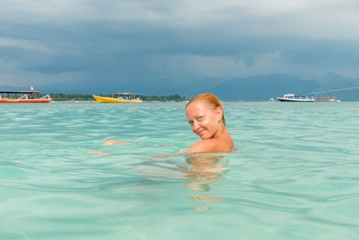 Woman at tropical island beach swimming in lush blue water