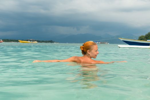 Woman at tropical island beach swimming in lush blue water