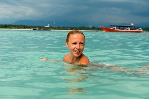 Woman at tropical island beach swimming in lush blue water