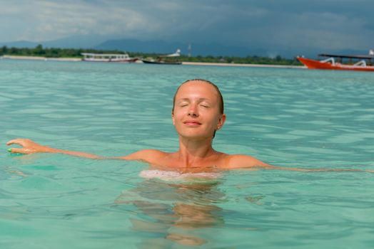 Woman at tropical island beach swimming in lush blue water