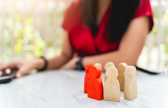 Figure in human resource management concept. The group of wooden puppets is a circular. A red wooden figure like an dominant in a group with blur owner or manager background
