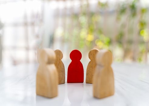 Figure in human resource management concept. The group of wooden puppets is a circular. A red wooden figure like an dominant in a group with blur bokeh background
