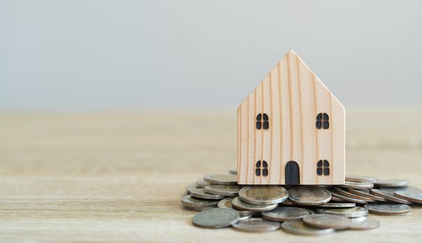 Money savings concepts. Wooden house models with coins in meaning about saving money to buy a house, refinancing, investment or financial on wooden table with blur background and copy space