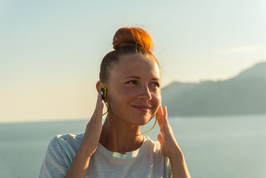 Fitness girl with sport in-ear wireless headphones - Caucasian female athlete woman wearing Bluetooth earphones