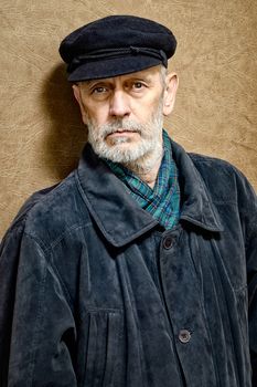 Portrait of a mature man with a white beard and a cap on the head. He could be a sailor, a worker, a docker, or even a gangster or a thug. He has a penetrating gaze.