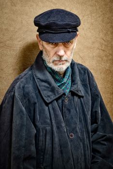 Portrait of a mature man with a white beard and a cap on the head. He could be a sailor, a worker, a docker, or even a gangster or a thug. He has a penetrating gaze.