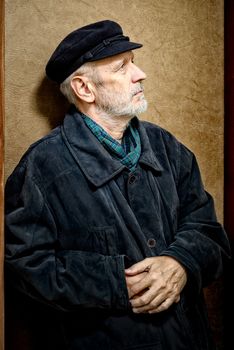 Portrait of a mature man with a white beard and a cap on the head. He could be a sailor, a worker, a docker, or even a gangster or a thug. He is looking up.