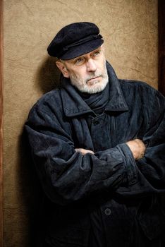 Portrait of a mature man with a white beard and a cap on the head. He could be a sailor, a worker, a docker, or even a gangster or a thug. He has a penetrating gaze.