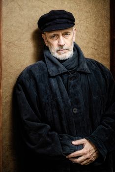 Portrait of a mature man with a white beard and a cap on the head. He could be a sailor, a worker, a docker, or even a gangster or a thug. He has a penetrating gaze.