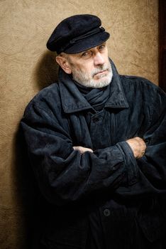 Portrait of a mature man with a white beard and a cap on the head. He could be a sailor, a worker, a docker, or even a gangster or a thug. He has a penetrating gaze.